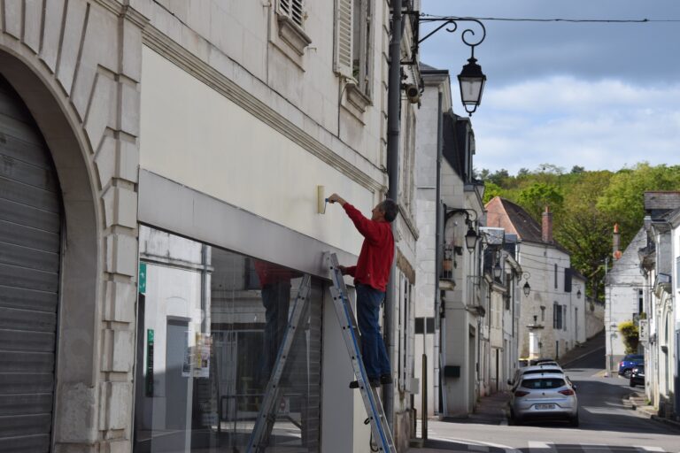 Un bénévole en train de peintre les anciennes enseignes